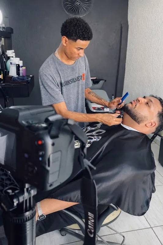 Barbeiro atendendo um cliente com uma câmera Canon em primeiro plano